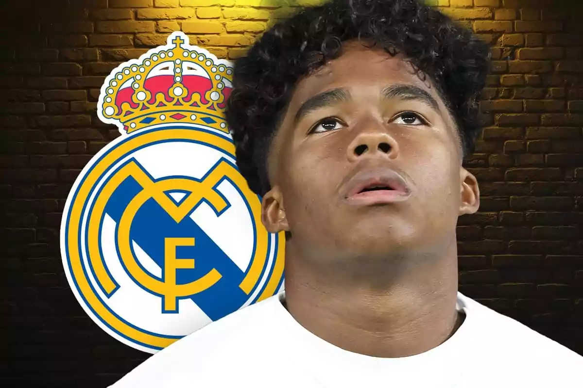 Joven futbolista con camiseta blanca frente al escudo del Real Madrid sobre un fondo de ladrillos.