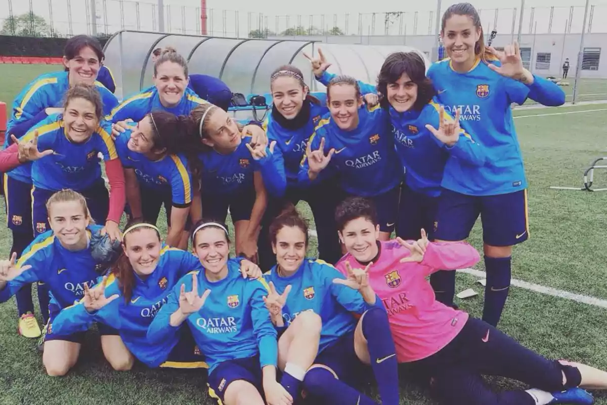 Un grupo de jugadoras de fútbol sonríe y posa en un campo de entrenamiento.