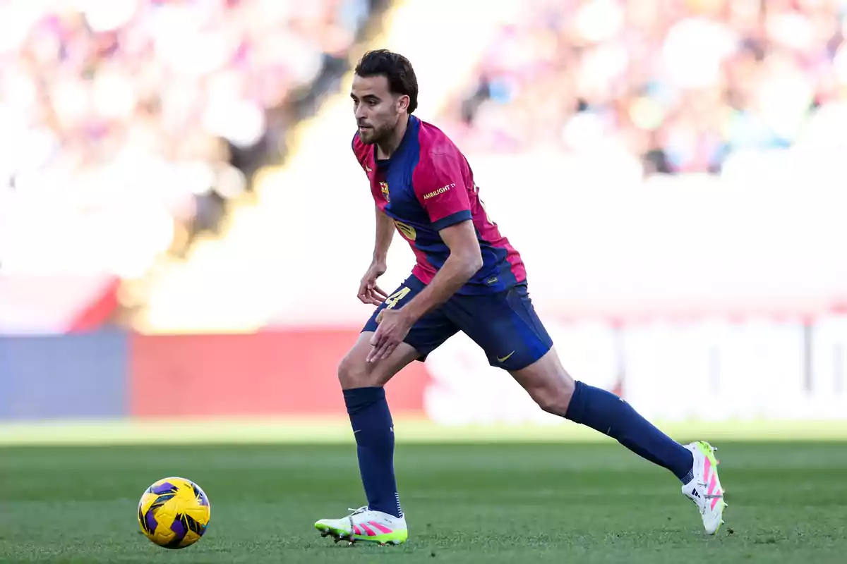 Un jugador de fútbol con uniforme azul y rojo corre en el campo mientras controla el balón. Un jugador de fútbol con uniforme azul y rojo corre en el campo mientras controla el balón.