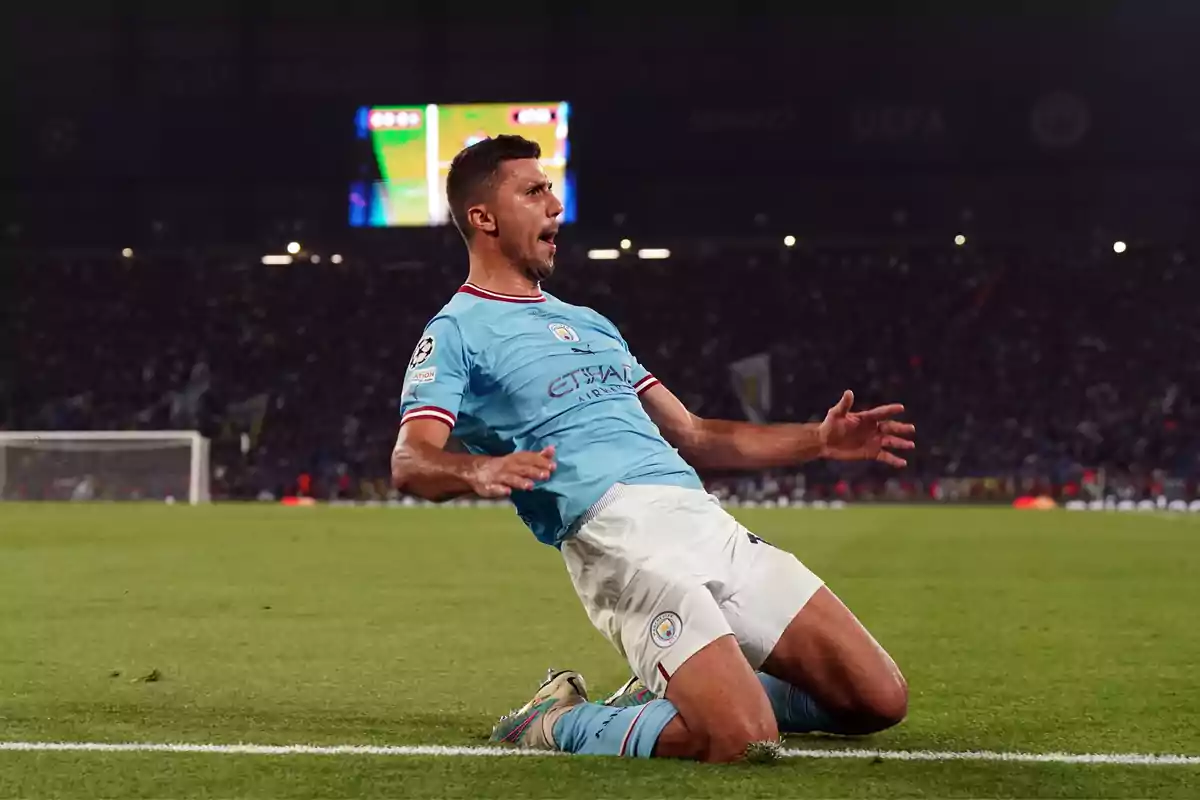 A soccer player celebrates by sliding on his knees on the grass during a night game.