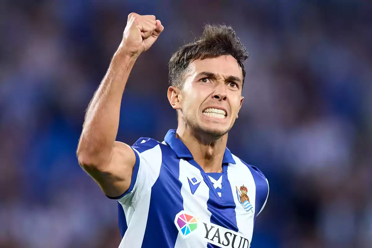 soccer player celebrating with his fist raised while wearing the Real Sociedad uniform.