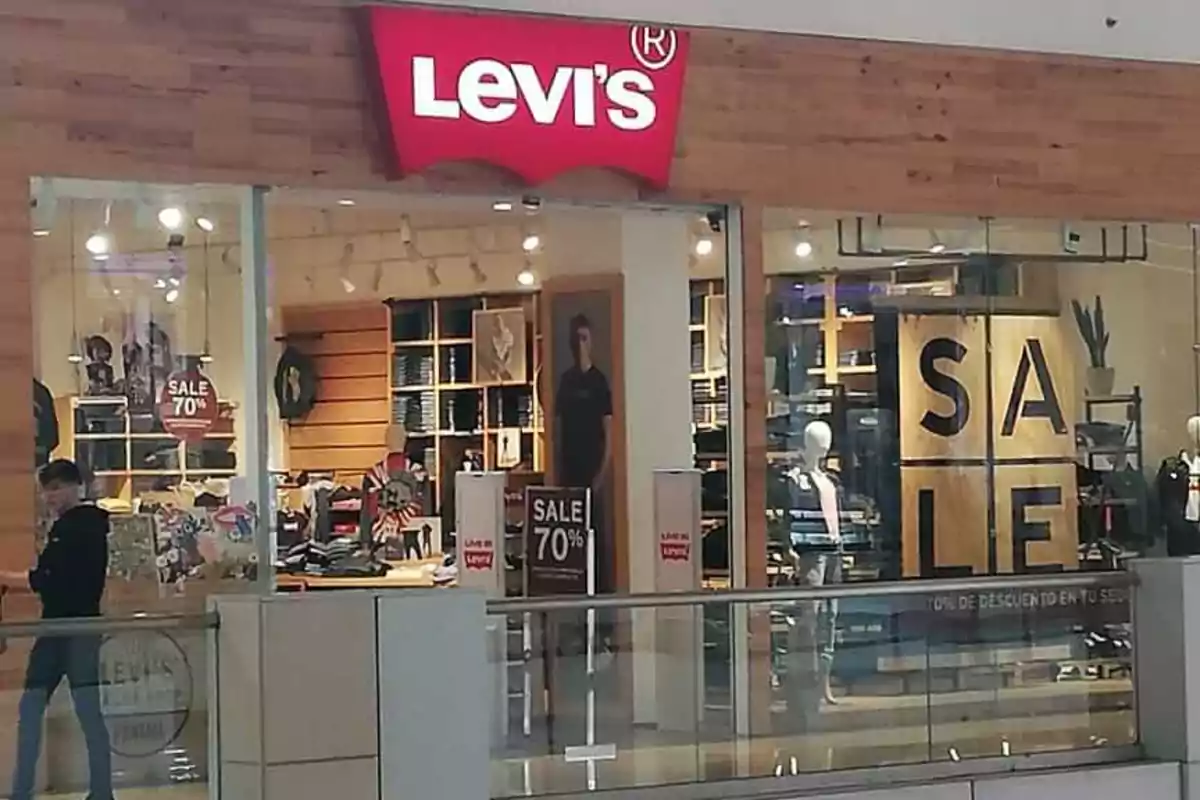 Tienda de ropa Levi's en un centro comercial con letreros de descuento del 70% y maniquíes en el escaparate. Tienda de ropa Levi's en un centro comercial con letreros de descuento del 70% y maniquíes en el escaparate.