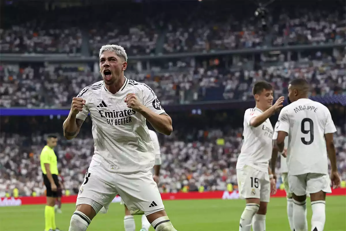 Jugadores de fútbol celebrando un gol en el Santiago Bernabéu lleno de aficionados.