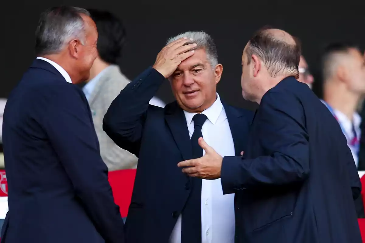 Three men in suits chat at a formal event.