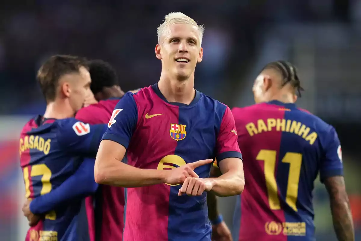 A FC Barcelona soccer player celebrates on the field while other players hug in the background.