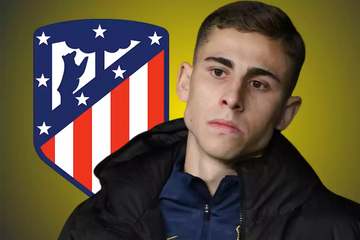 Un hombre con chaqueta oscura frente al escudo del Atlético de Madrid sobre un fondo amarillo.