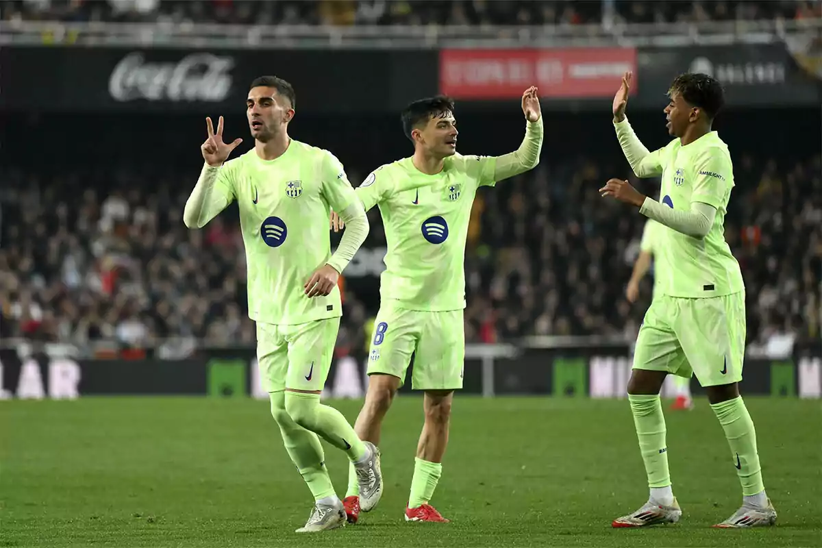 Soccer players celebrating on the field in green uniforms.