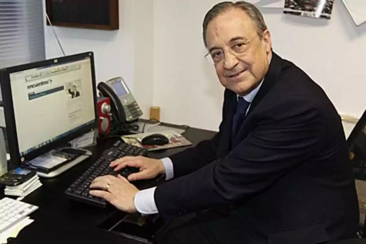 A man in a suit sitting at a desk using a computer.