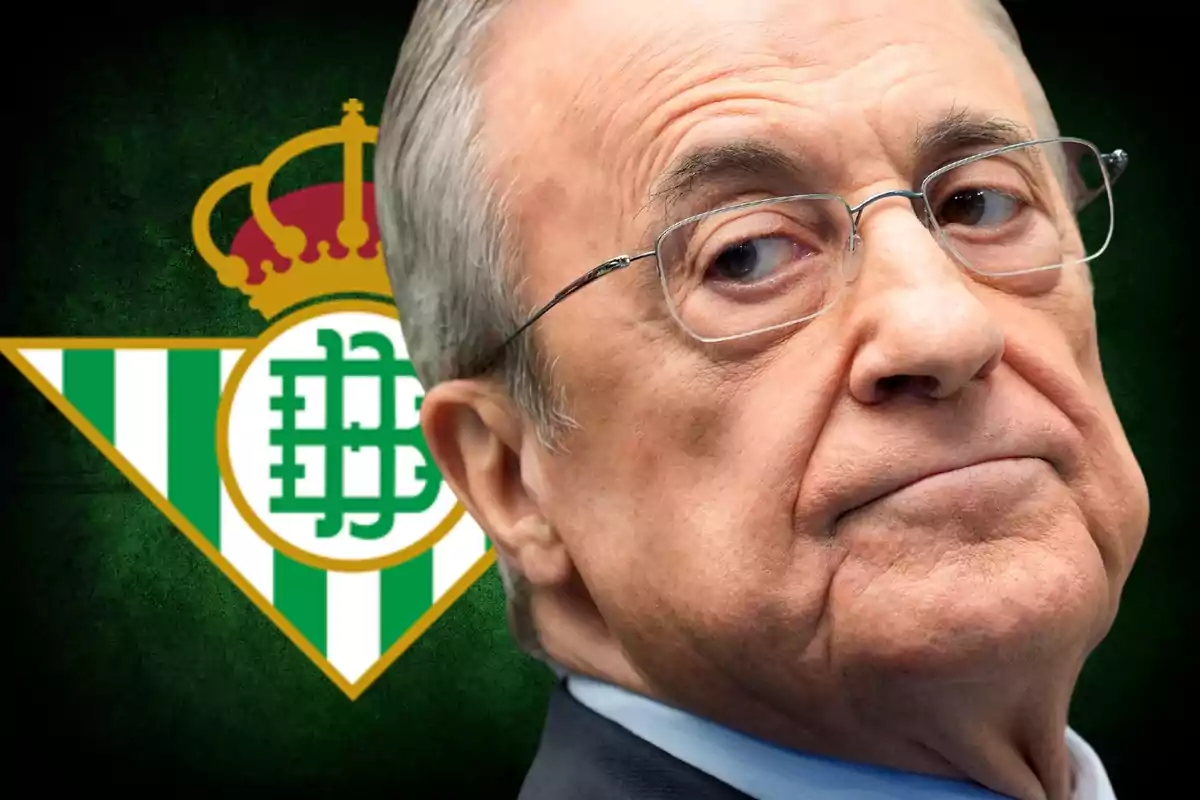 Man with glasses in front of the Real Betis crest.