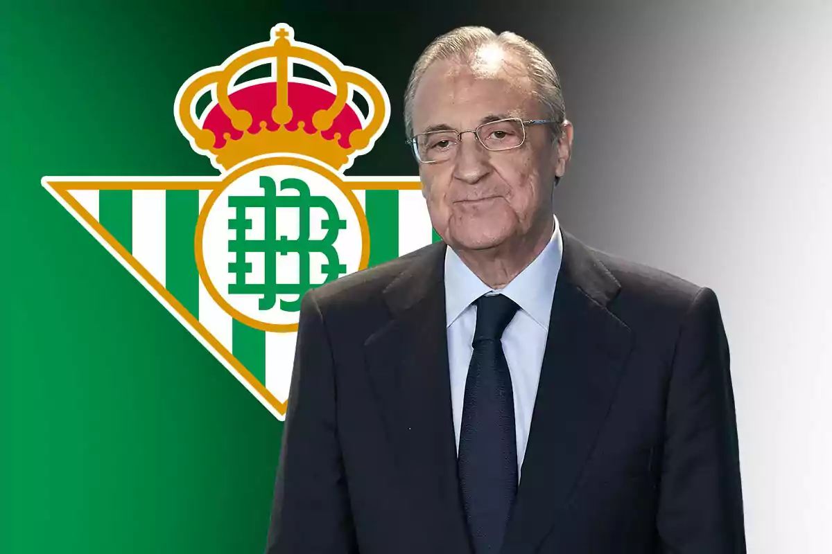 A man in a suit and tie in front of the Real Betis crest.