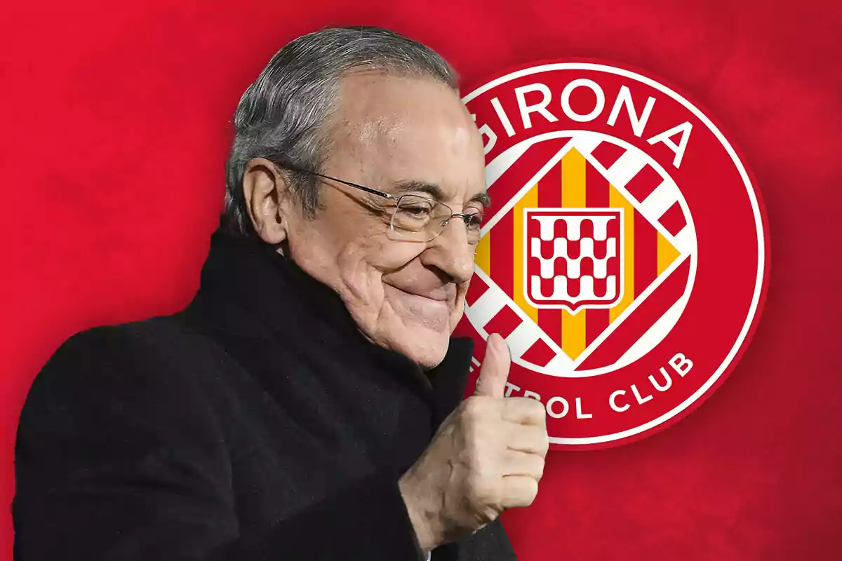 Un hombre mayor con gafas y abrigo oscuro hace un gesto de aprobación con el pulgar levantado frente al logo del Girona FC sobre un fondo rojo.