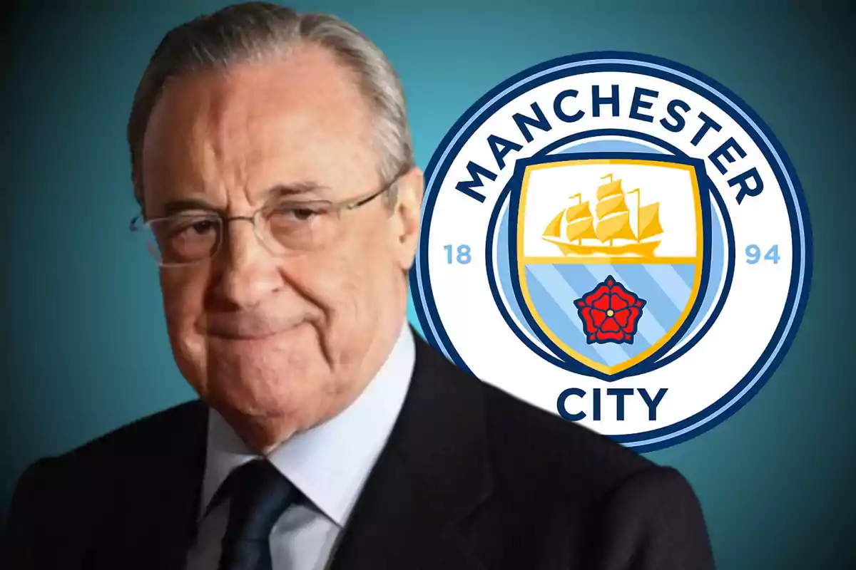 A man with glasses and a suit in front of the Manchester City crest.