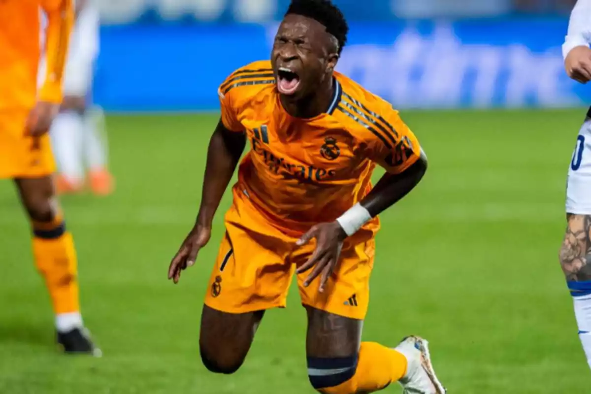 Soccer player in orange uniform showing pained expression on the field.