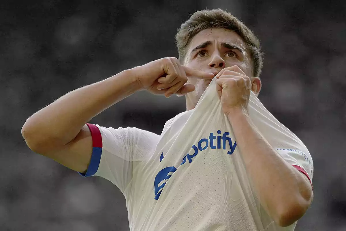 Gavi celebrando un gol mientras sostiene y besa la camiseta del FC Barcelona.