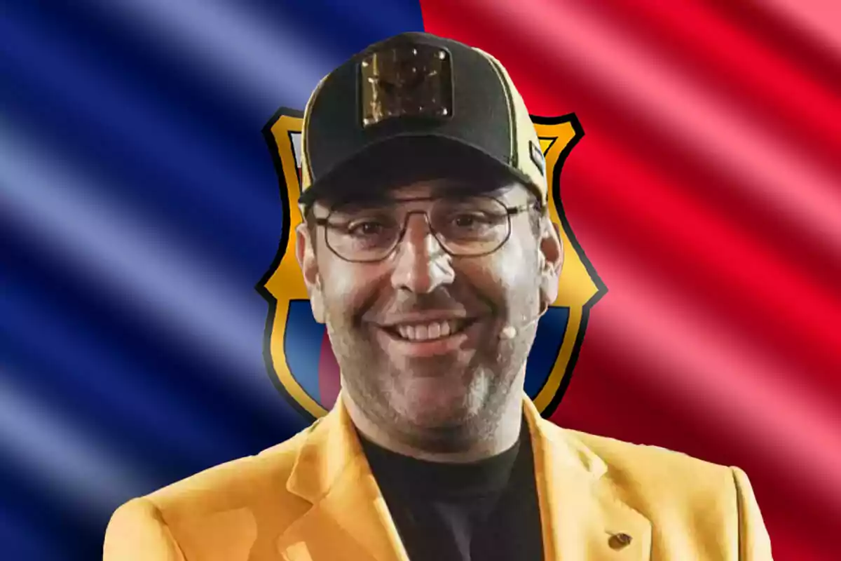 Gerard Romero sonriendo, detrás una bandera del Barcelona