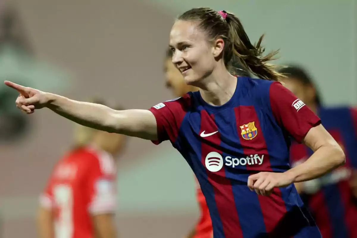 Jugadora de fútbol del FC Barcelona celebrando un gol mientras señala con el dedo.