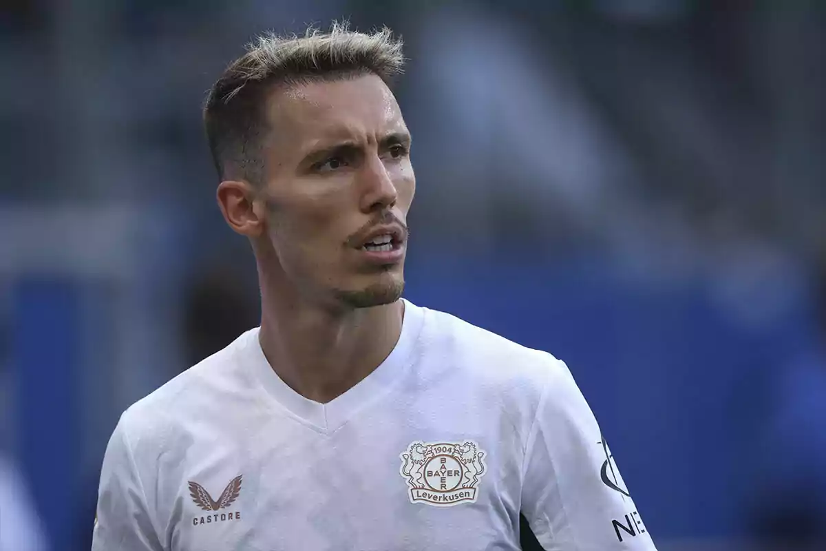 A soccer player in a white Bayer Leverkusen jersey on the field.