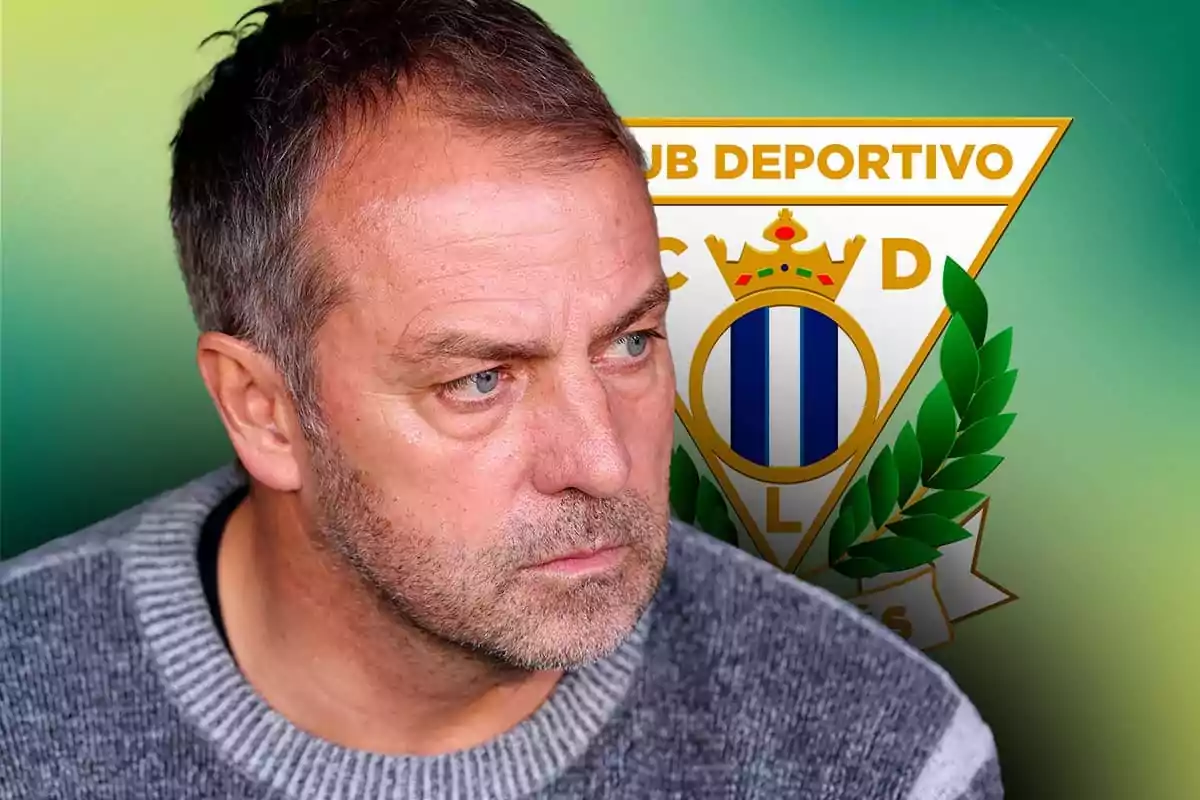 Hansi Flick in a grey sweater in front of CD Leganés crest.