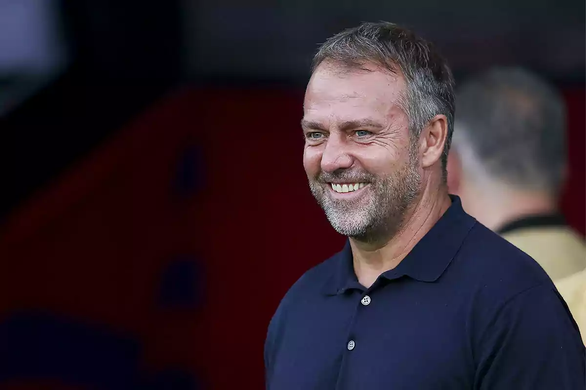 Hansi Flick with a beard and short hair wears a dark polo jersey.