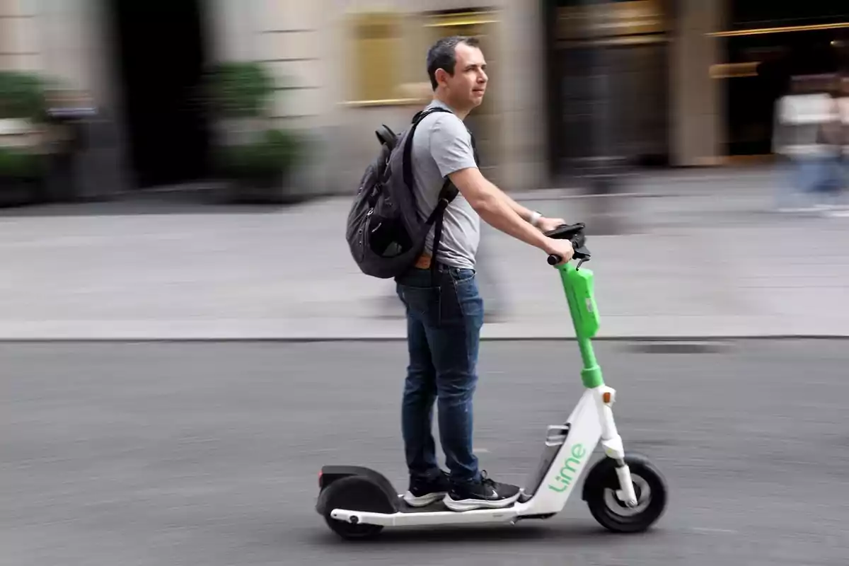 Hombre con mochila montando un scooter eléctrico Lime en una calle urbana.