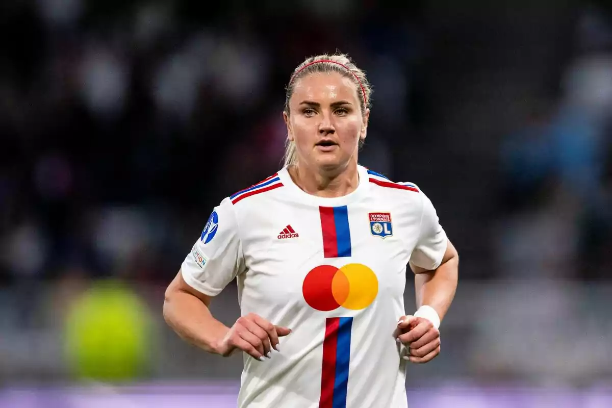 Una jugadora de fútbol con el uniforme del Olympique de Lyon en el campo.