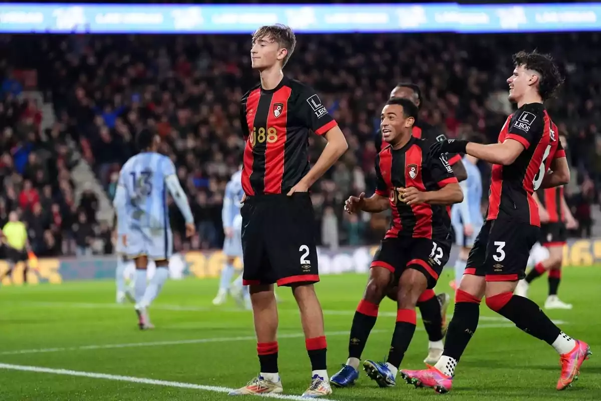 Soccer players celebrating a goal in a stadium full of spectators.