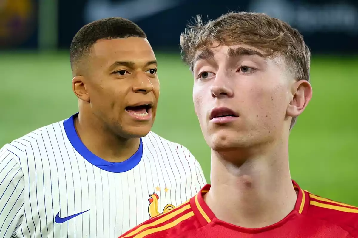 Two players wearing their national team uniforms, one in a white France jersey and the other in a red Spain jersey, on a soccer field.