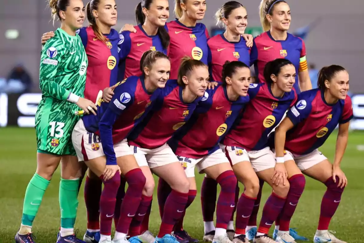 A women's soccer team posing for a group photo on the field.