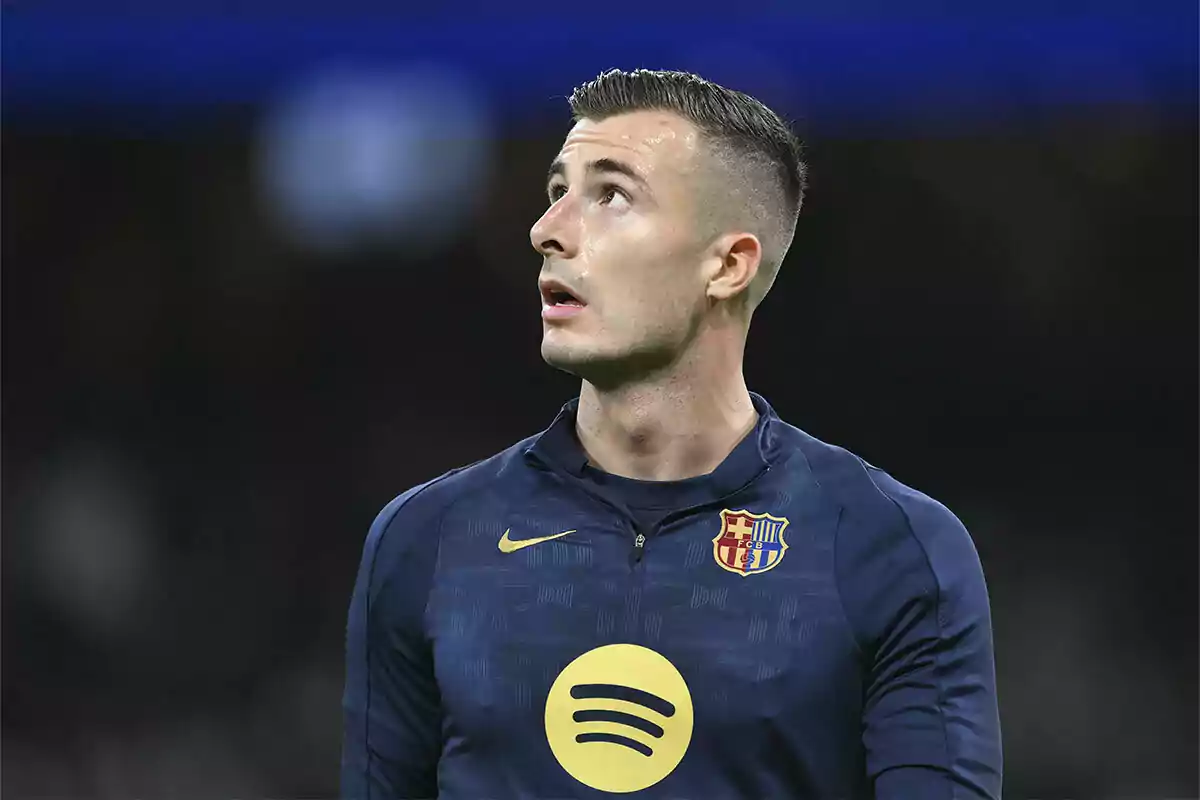 Un jugador de fútbol con uniforme azul oscuro del FC Barcelona mira hacia arriba en un estadio.