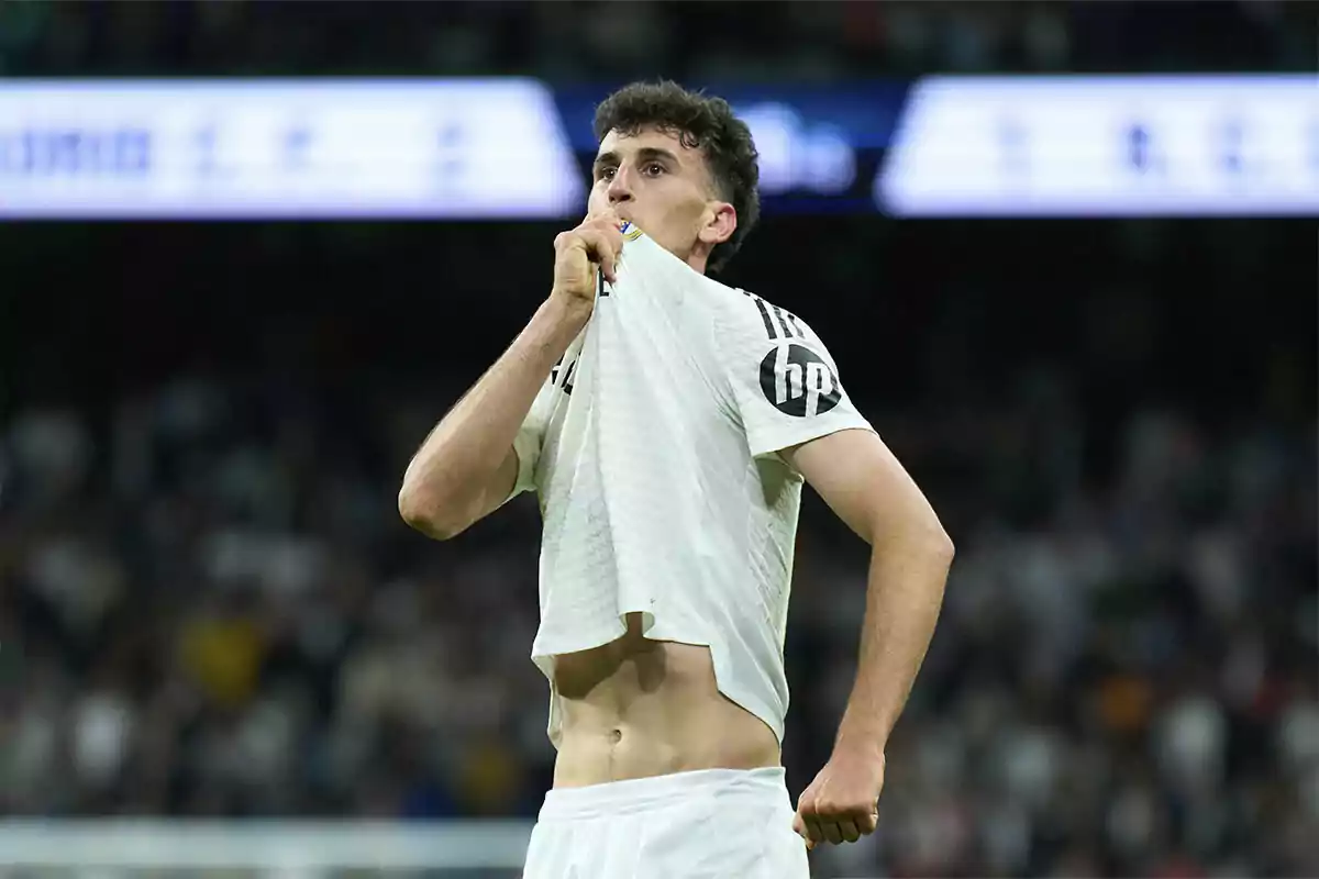 Futbolista besando el escudo de su camiseta en señal de celebración durante un partido Futbolista besando el escudo de su camiseta en señal de celebración durante un partido
