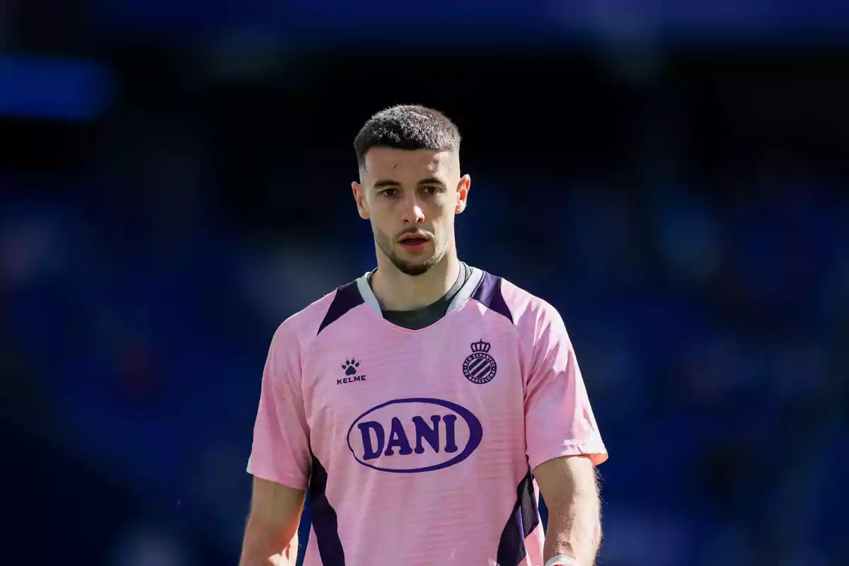 Un jugador de fútbol con camiseta rosa del RCD Espanyol en el campo. Un jugador de fútbol con camiseta rosa del RCD Espanyol en el campo.