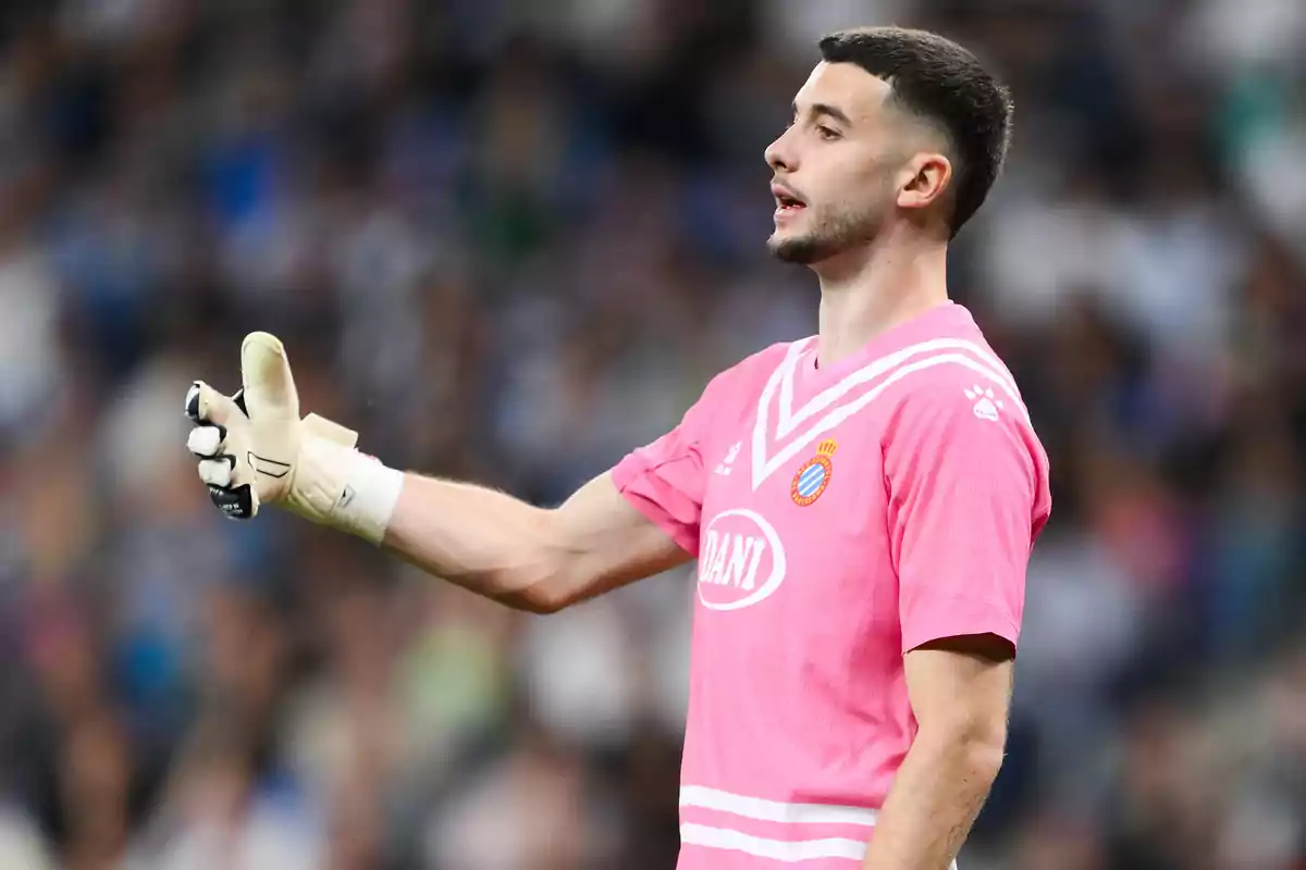 Soccer goalkeeper wearing a pink uniform and white gloves giving instructions during a match