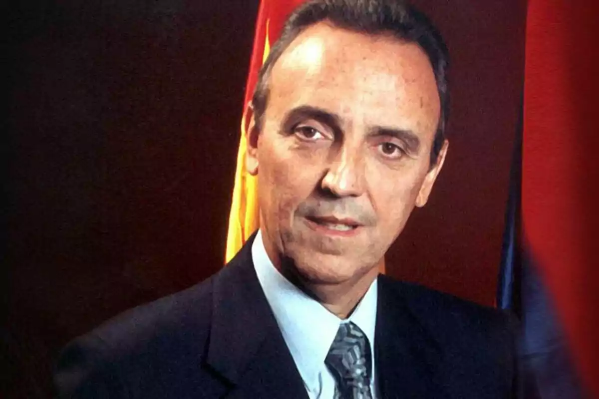 Joan Gaspart in a suit and tie in front of a dark background with a flag. Joan Gaspart in a suit and tie in front of a dark background with a flag.