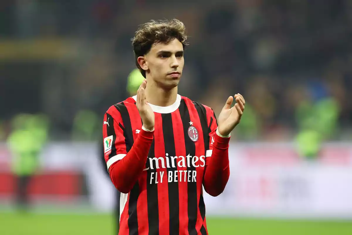 Un jugador de fútbol con el uniforme del AC Milan aplaude en el campo.