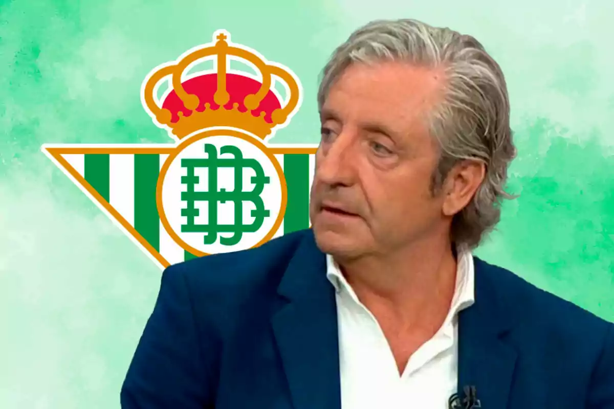 Un hombre de cabello canoso y traje azul está frente a un fondo con el logo del Real Betis.