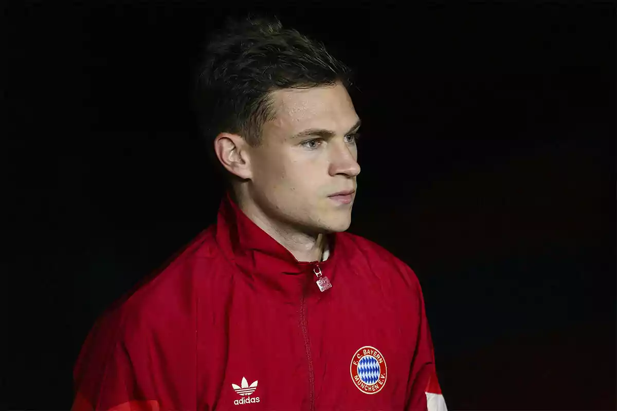 Joshua Kimmich in a red Bayern Munich jacket against a dark background.