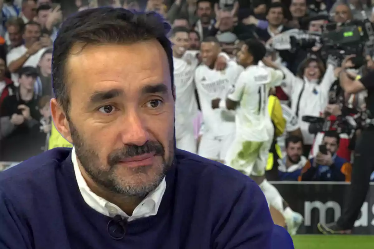 Un hombre con barba y suéter azul aparece en primer plano mientras en el fondo se ve a un grupo de jugadores de fútbol celebrando en un estadio lleno de espectadores.