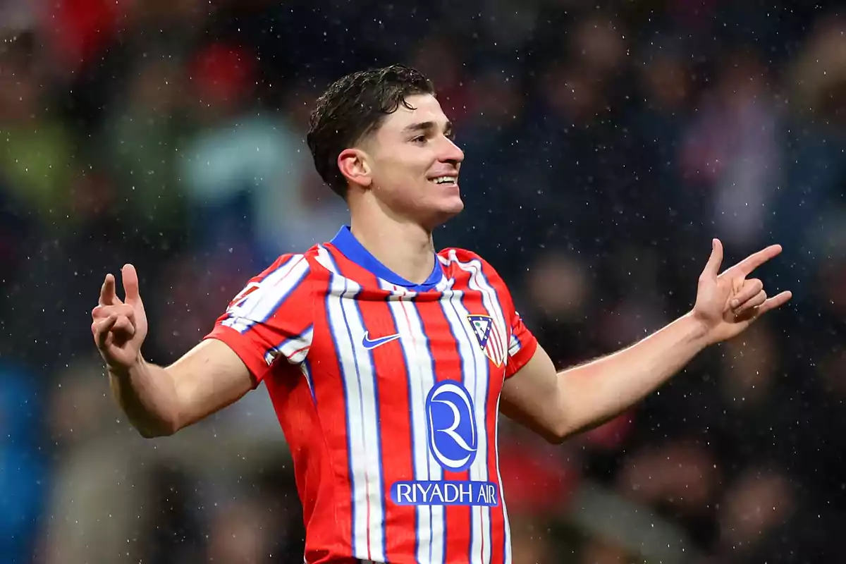 A player in a red and white uniform celebrates on the field in the rain.