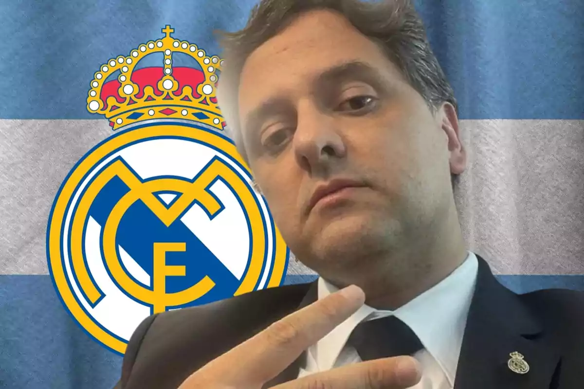 Man in a suit making a peace sign in front of the Real Madrid crest on a blue and white flag
