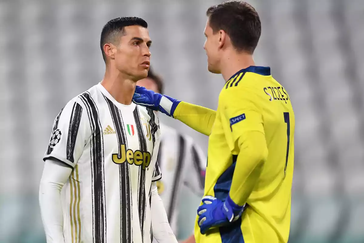 Two soccer players on the field, one in a black and white uniform and the other in a yellow uniform, interact during a match.