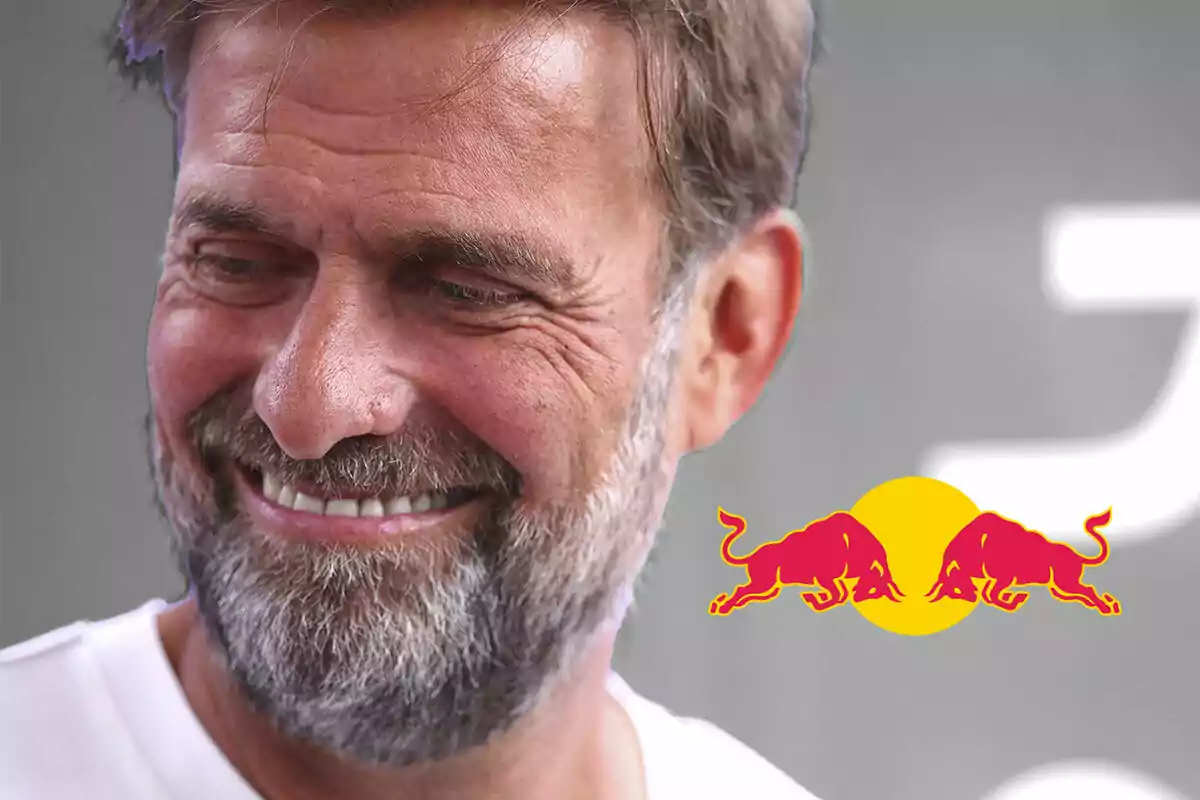 Jürgen Klopp, sonriente con barba y cabello castaño claro, con el logo de Red Bull en el fondo.