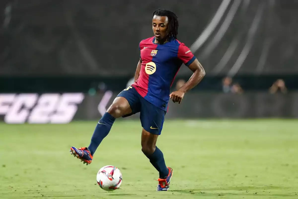 Soccer player in blue and red uniform controlling the ball on the playing field.