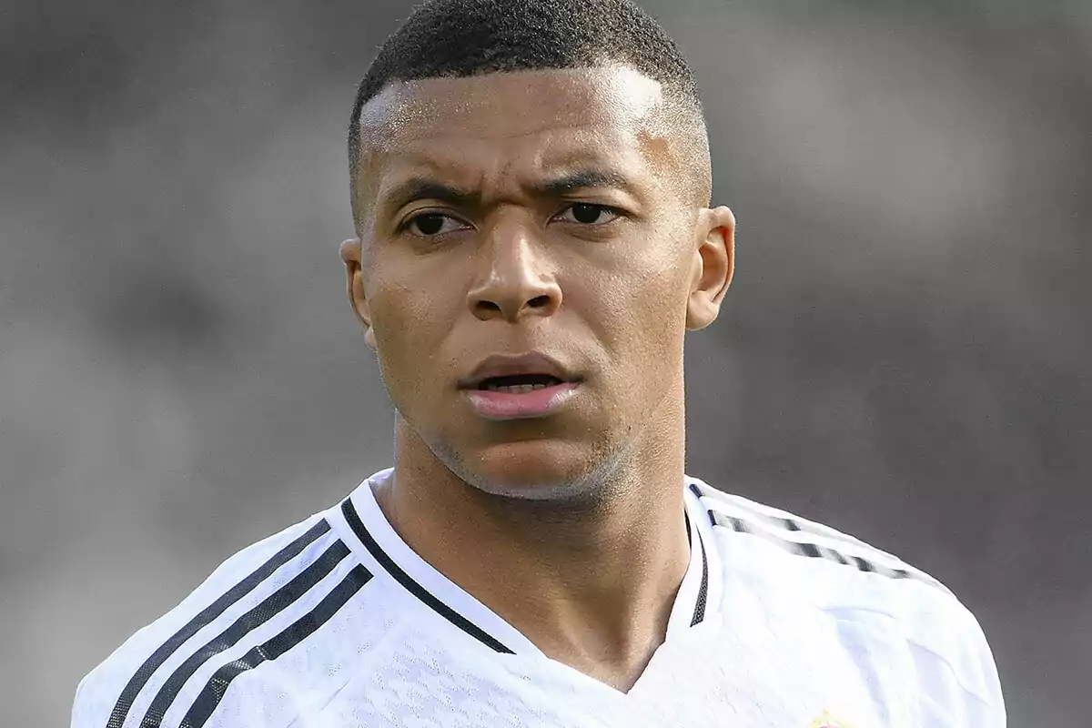 Soccer player wearing a white jersey with black details looking straight ahead with a serious expression