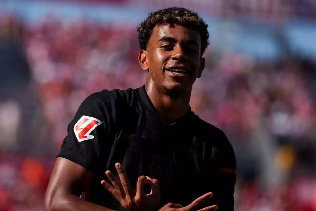 Jugador de fútbol celebrando en el campo con una camiseta negra.