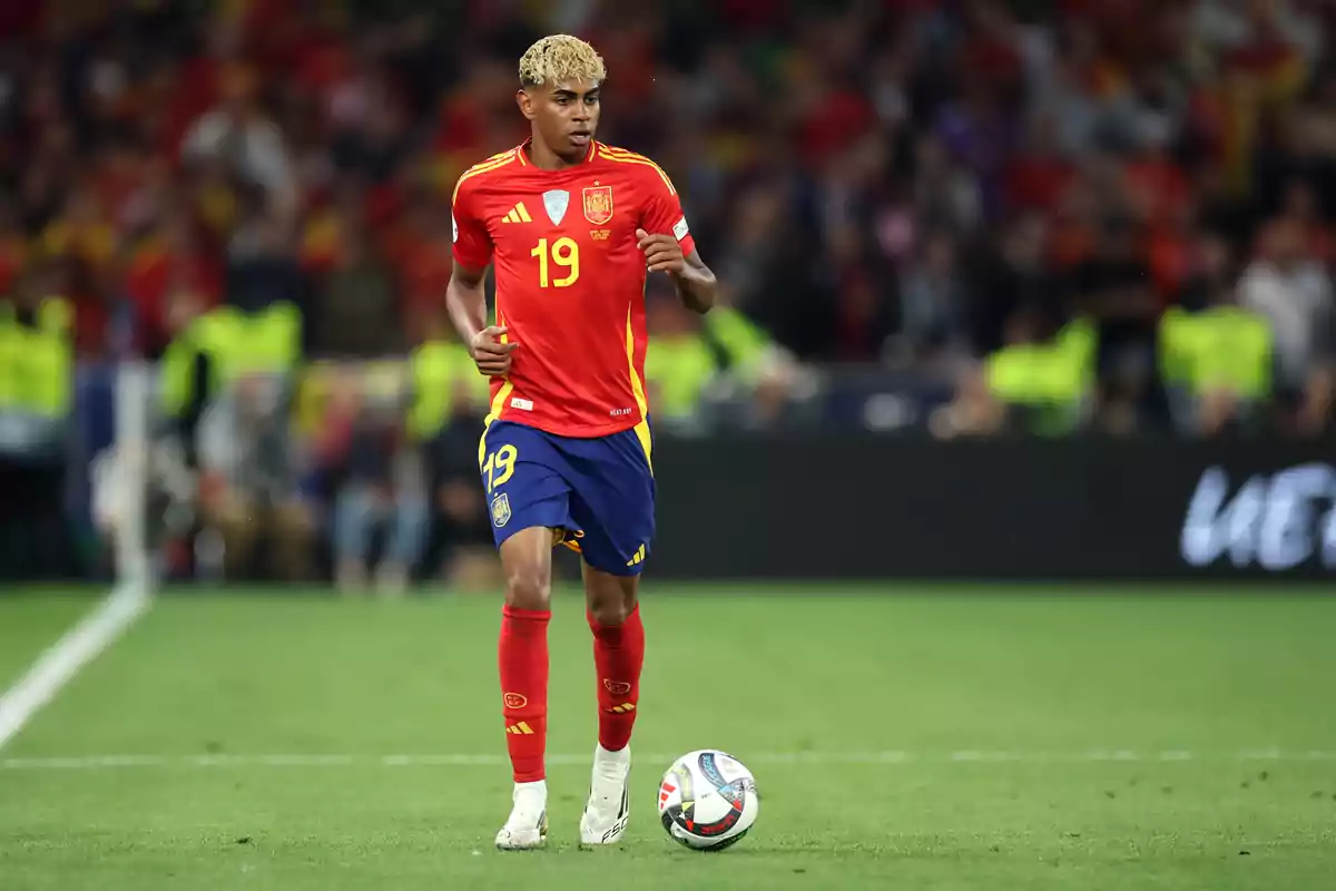Soccer player wearing the red and blue uniform of the Spanish national team controls the ball during a match.