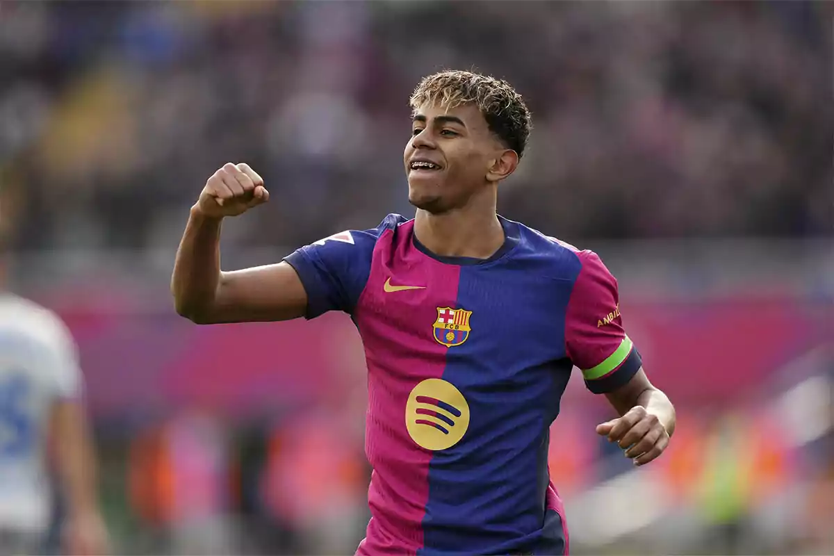 Un jugador de fútbol con uniforme azul y rosa celebra en el campo.