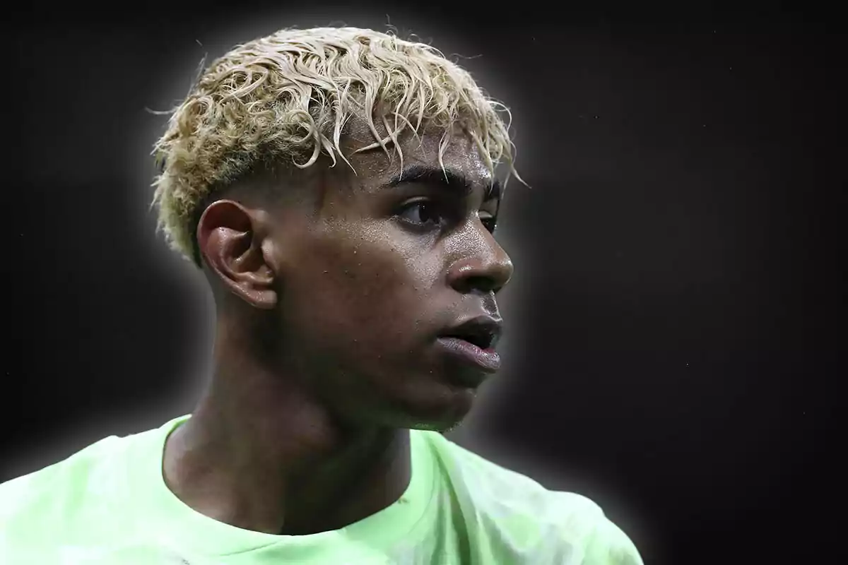 Un jugador de fútbol con cabello rubio y rizado mira hacia un lado en un fondo oscuro.