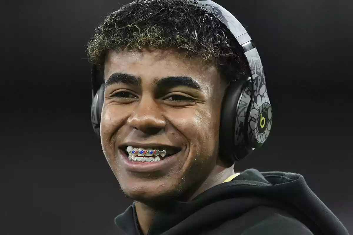 A smiling young man with hearing aids and colorful braces.