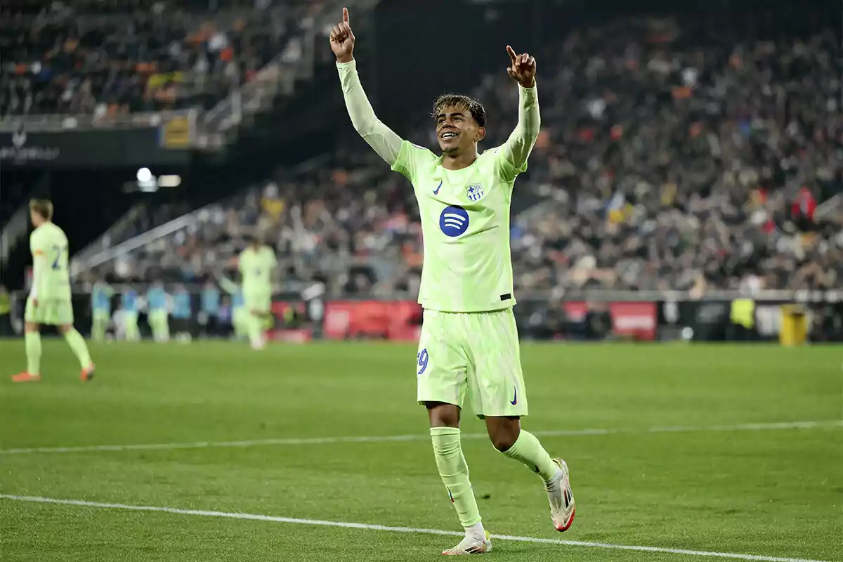 A player celebrates with arms raised in a stadium full of spectators.