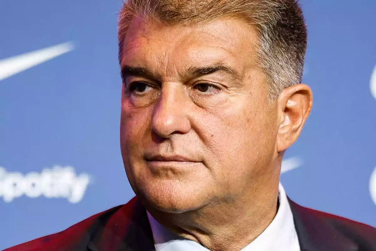 Joan Laporta looking to the side with a serious face on a blue background